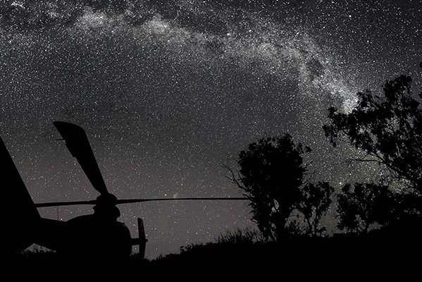 A helicopter is silhouetted against the Milky Way