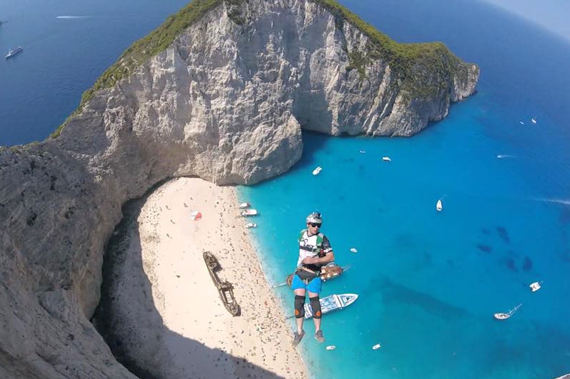 A BASE jumper falls through the air over an idyllic beach.