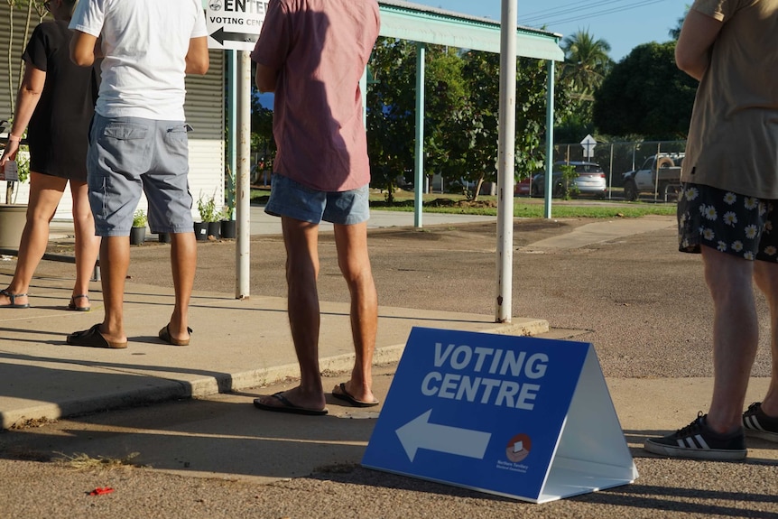 People stand in line outside a voting centre.