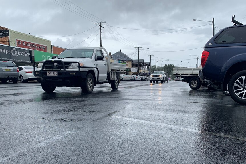 A ute drives down the main street of Stanthorpe, there are grey skies and rain on the ground.