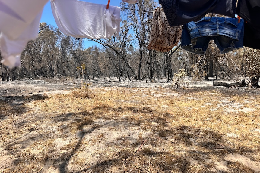 Clothes hang on a clothesline, with burnt ground from the fire just metres from it.