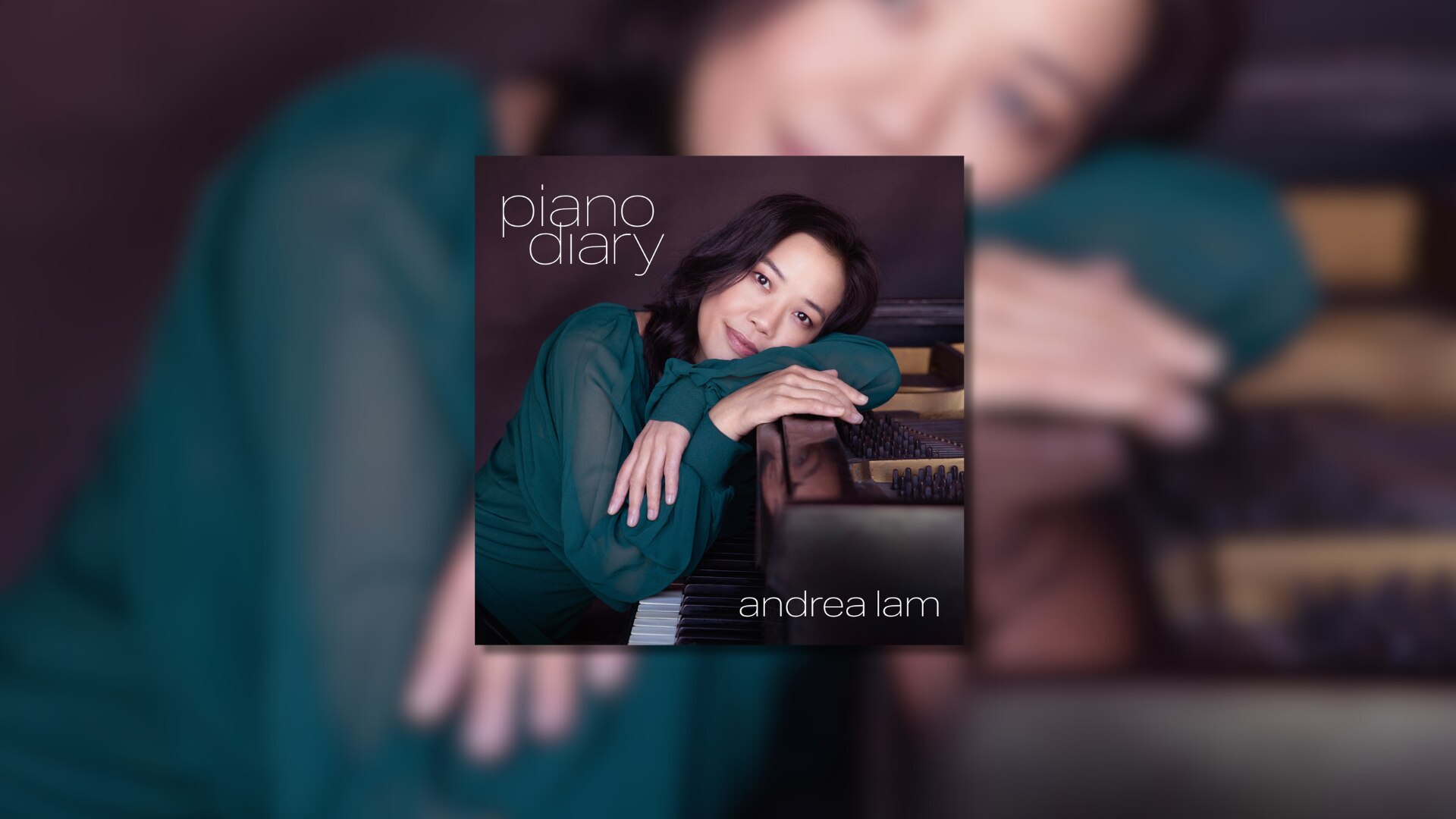 Closeup of young woman sitting at the piano, leaning across the keyboard, head resting on her arms, smiling.