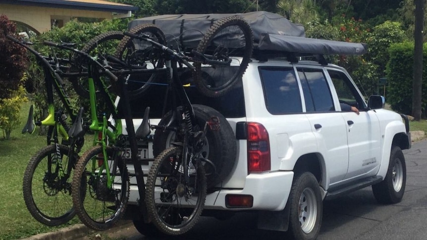 a car with five bikes on the back covering the rego
