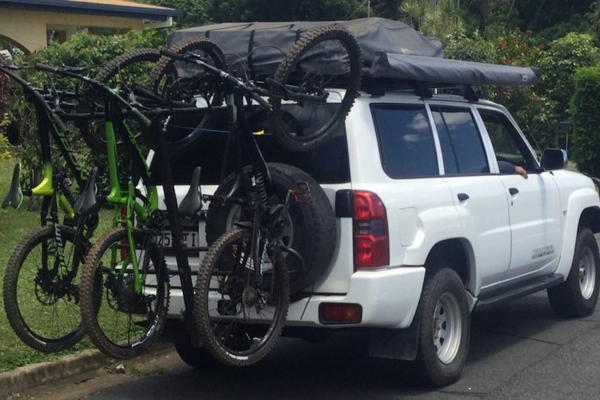 a car with five bikes on the back covering the rego