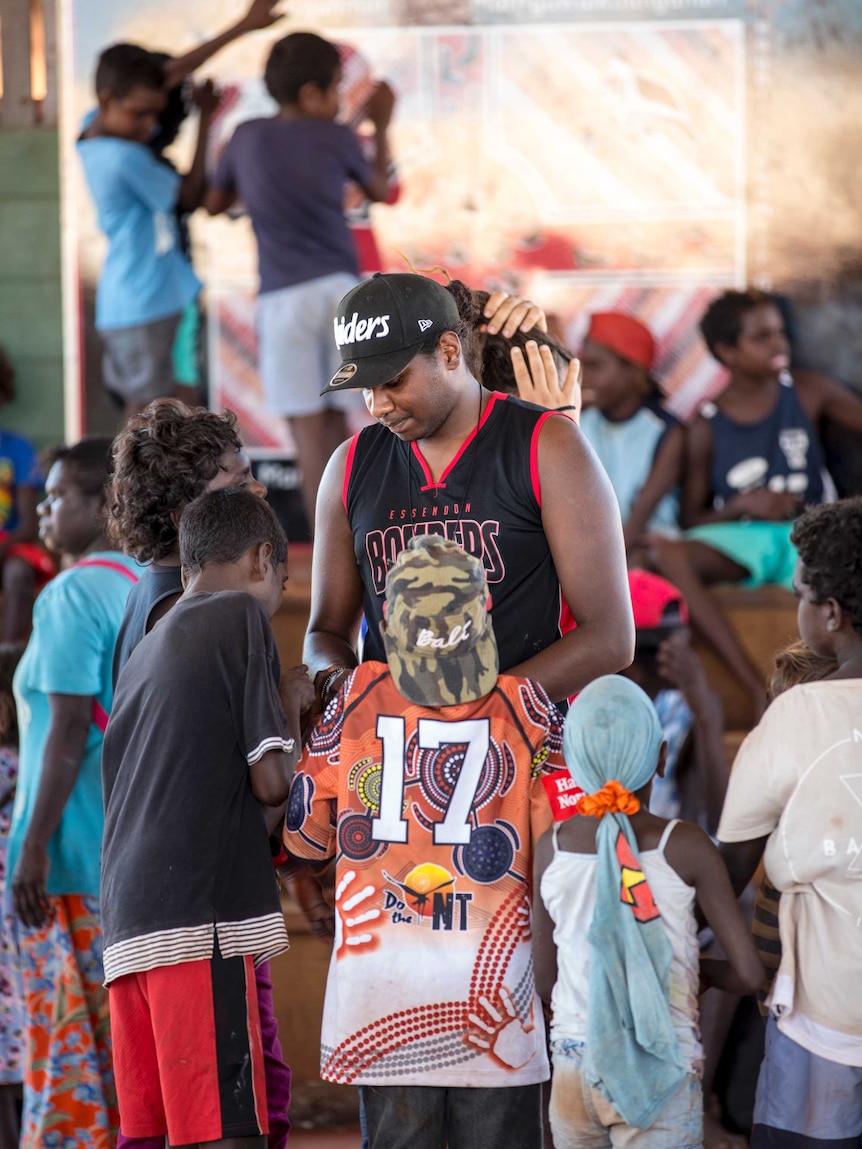 Danzal Baker stands among a group of small kids