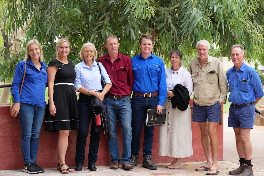 A group of farmers standing outside courthouse in front of trees