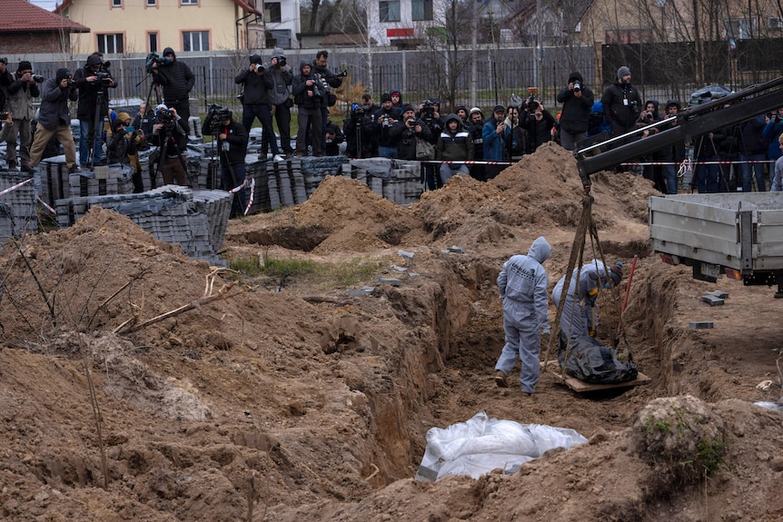 公墓工人从万人坑中挖掘出在布查遇难的平民的尸体。