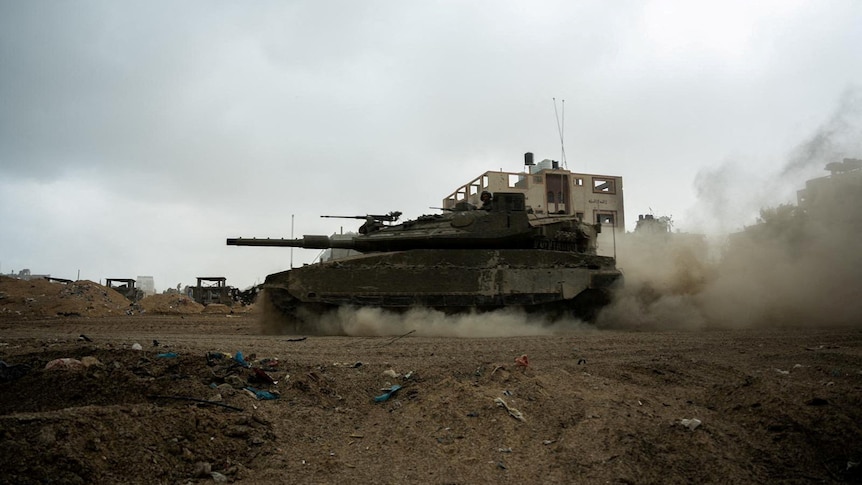 An Israeli soldier rides in a tank, amid the ongoing ground operation of the Israeli army in Gaza.