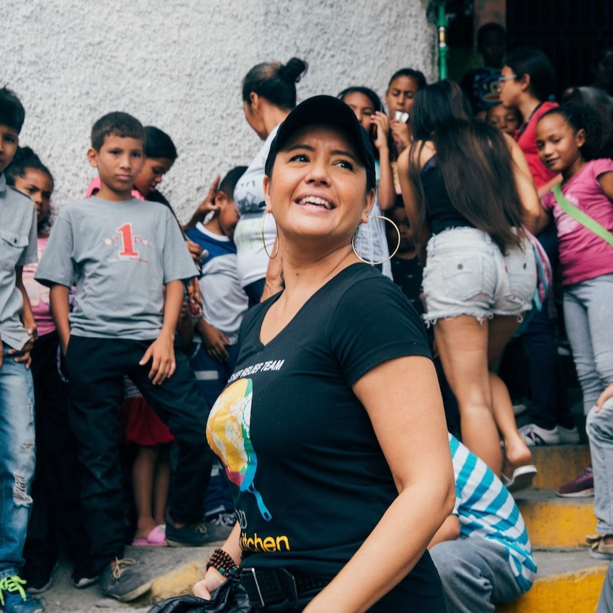 Image of Zomi Frankcom smiling while wearing a cap and a black t-shirt with the WCK logo. Behind her are a lot of kids.