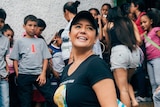 Image of Zomi Frankcom smiling while wearing a cap and a black t-shirt with the WCK logo. Behind her are a lot of kids.