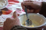 Elderly homeless man eats dessert at Mercy Arms day care centre.
