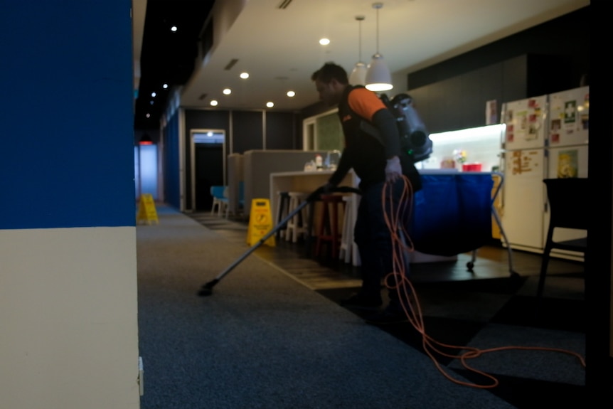 An unidentified cleaner vaccums in a building.