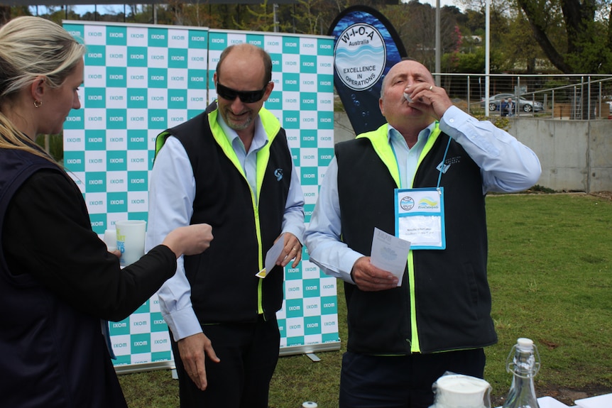 Judges sample water from small plastic cups.