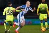 Aaron Mooy turns past a man while playing for Huddersfield Town.