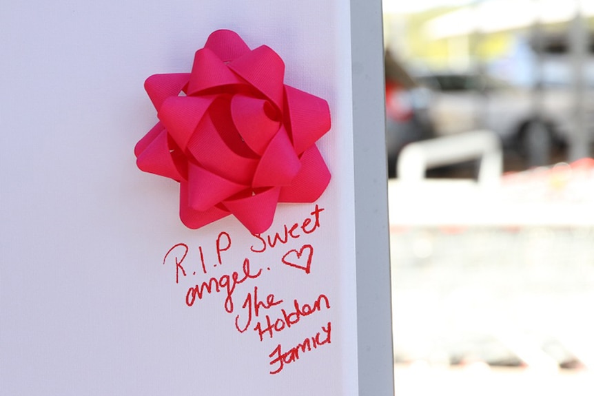 A ribbon stuck to a message board with the message "RIP sweet angel"