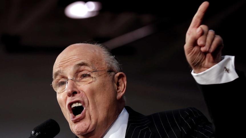 Rudy Giuliani gestures while introducing Donald Trump on stage