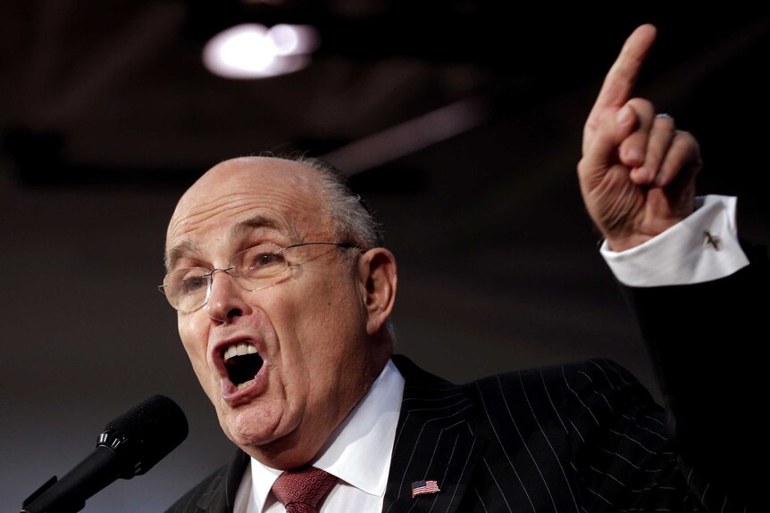 Rudy Giuliani gestures while introducing Donald Trump on stage