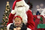 A child cries as she's placed on Santa Claus' knee for a photo.