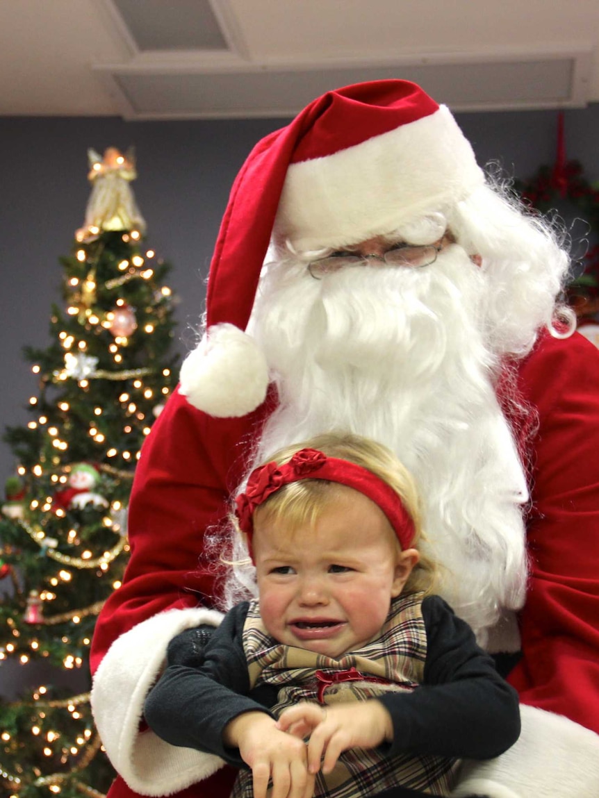 A child cries as she's placed on Santa Claus' knee for a photo.