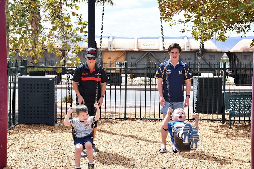 Two children are pushed on the swings in a Port Pirie park.