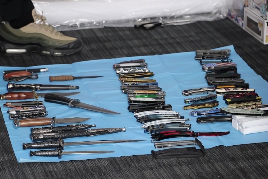 Dozens of knives laid out on the floor.