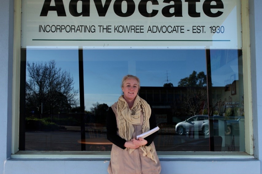 A woman standing in front of a newspaper office.