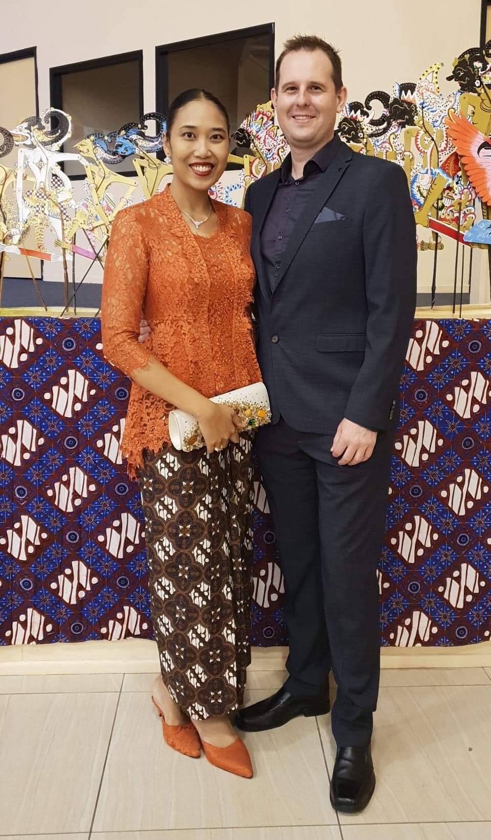 A woman wearing a pink shawl around her head and a man wearing black.