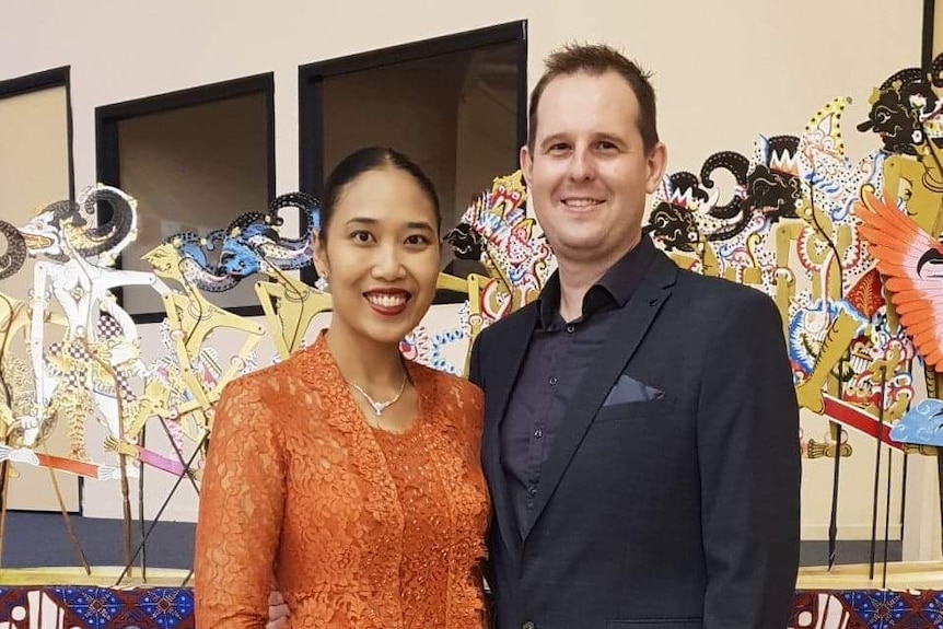 A woman wearing a pink shawl around her head and a man wearing black.