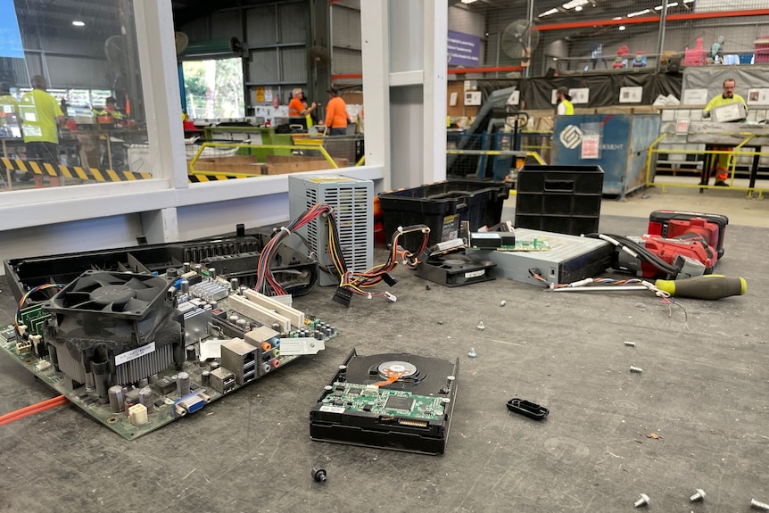 The internal components of a TV strewn across a work bench net to screws and a screwdriver