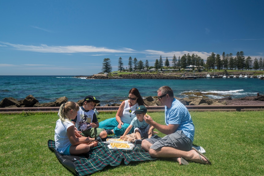 A family enjoys some fish and chips on the water in coastal town Kiama.