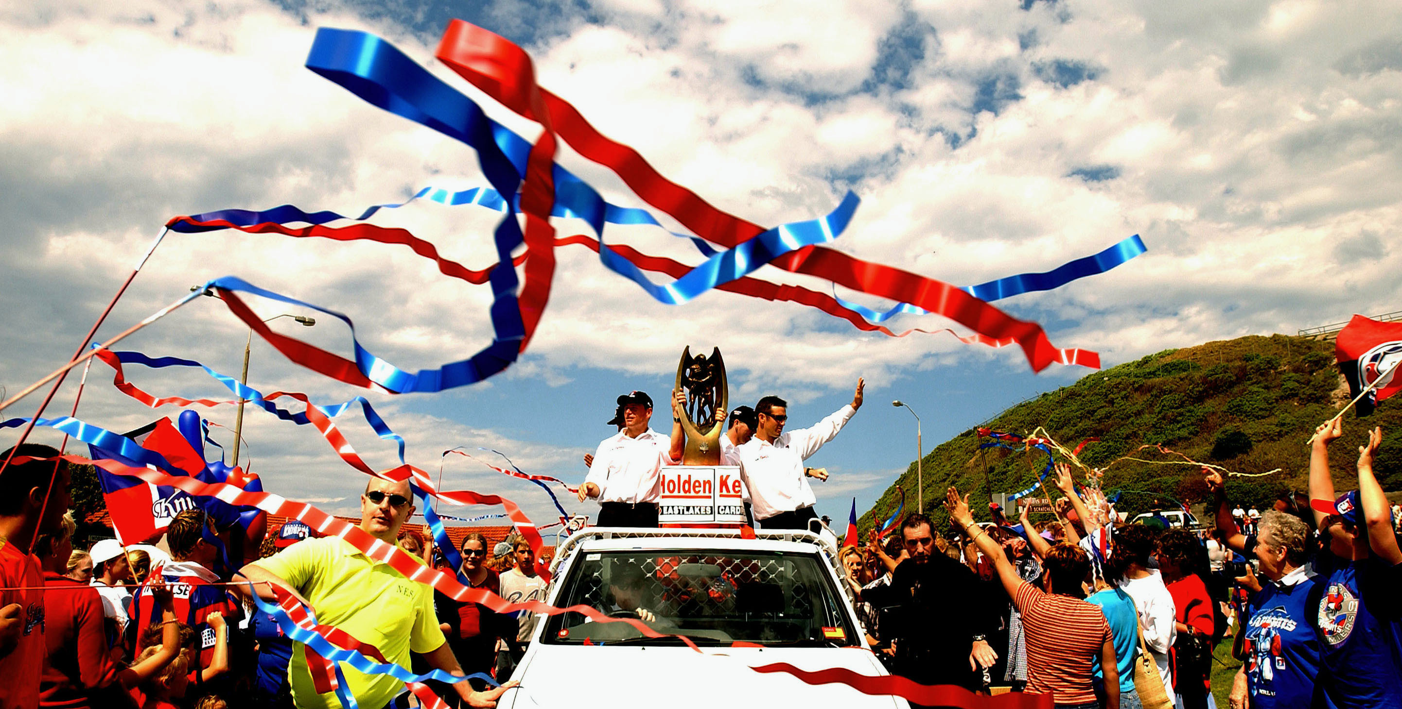 Two rugby league players take the premiership trophy through a parade