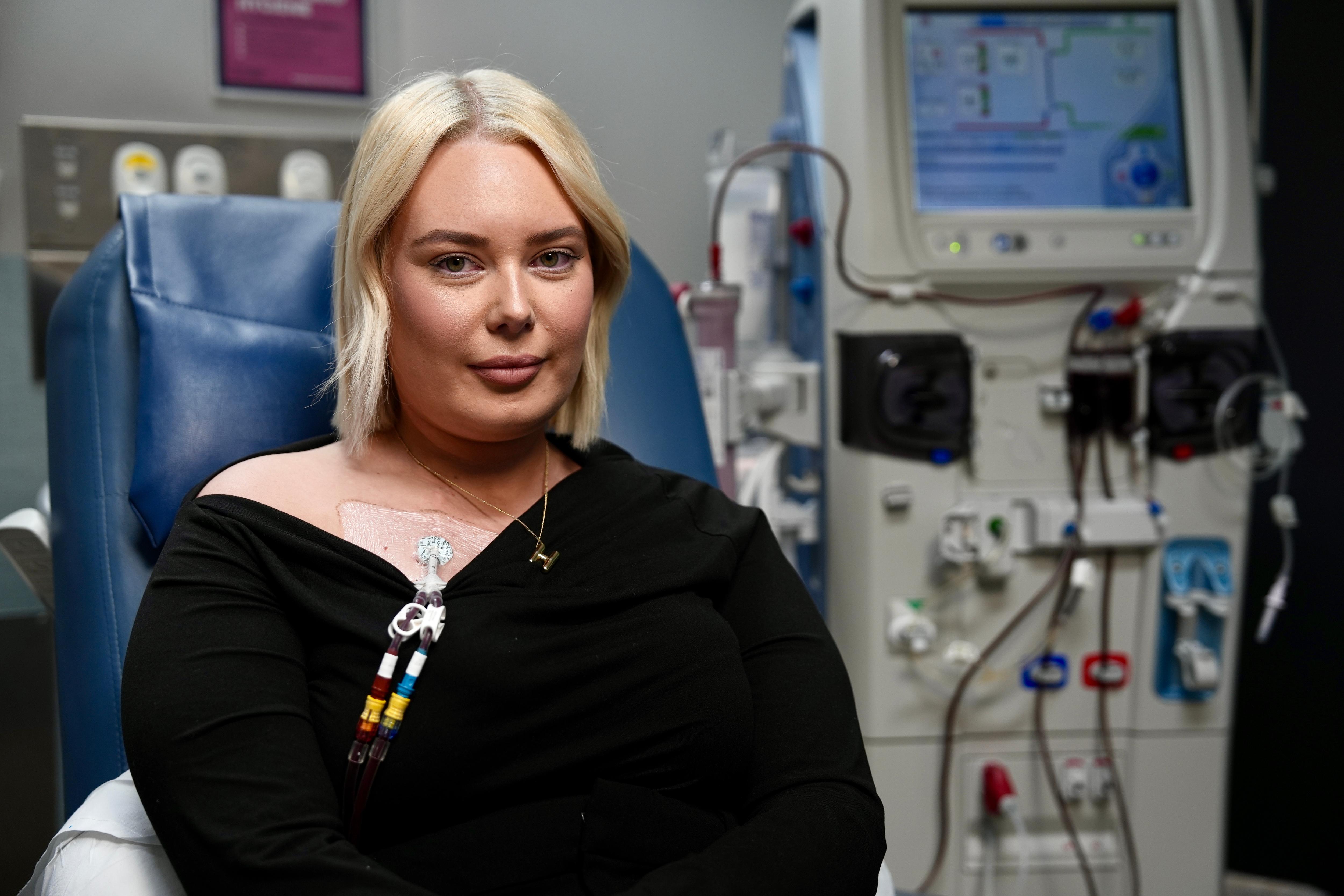A woman sits in hospital receiving dialysis treatment.