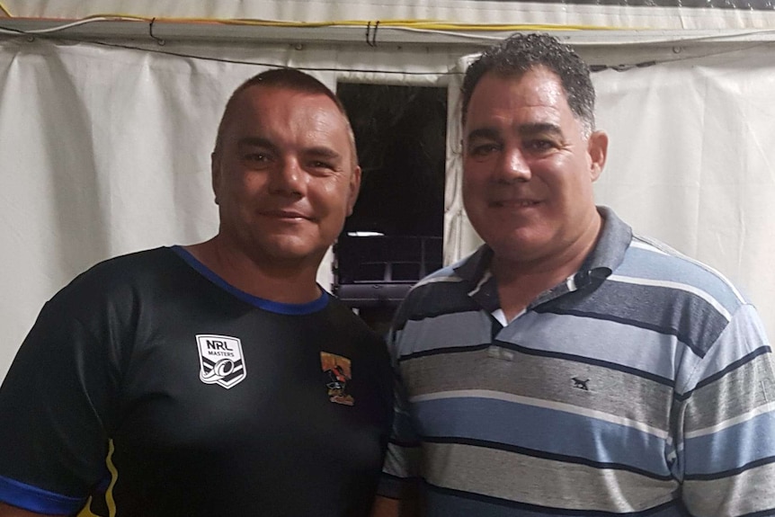 Two middle-aged men with short hair standing under a marquee.