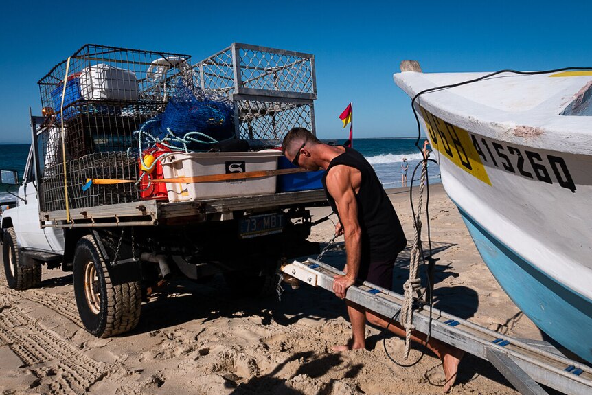 Man helps attach boat trailer to ute