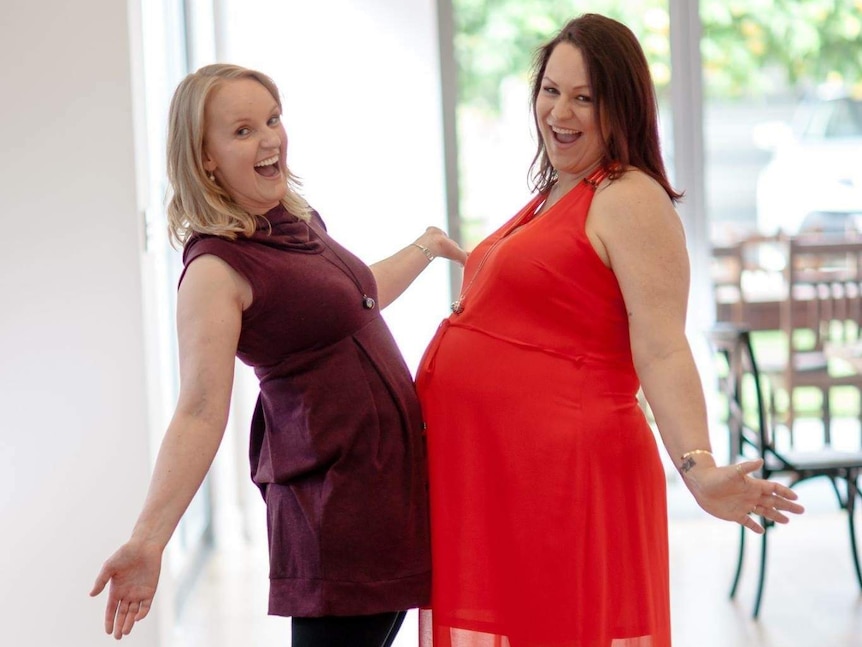 Rachel Kunde and Marian Sandberg press their stomachs together. Rachel is heavily pregnant.