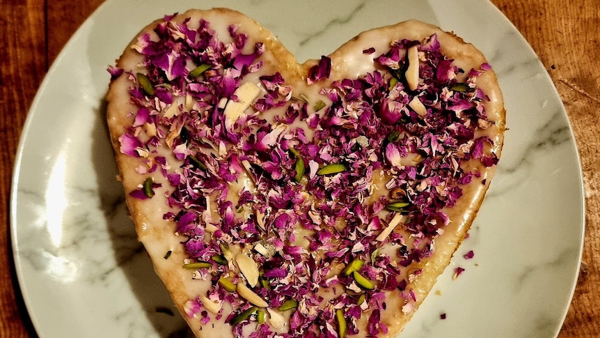 A heart-shaped cake sprinkled with petals