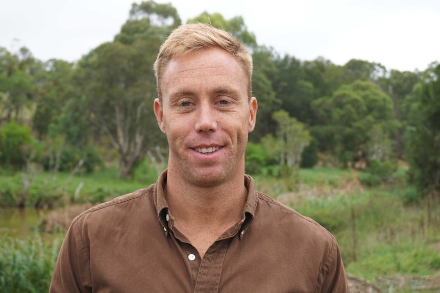 Dr Simon Clulow stands in front of wetlands on cloudy day