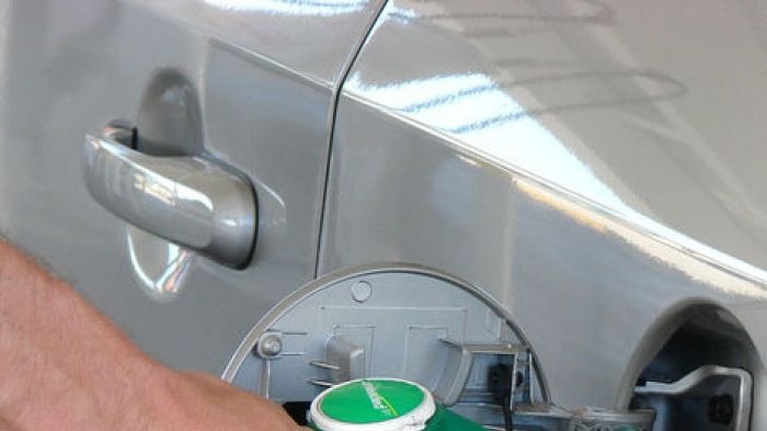 Hand pumping fuel into car