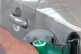 Hand pumping fuel into car