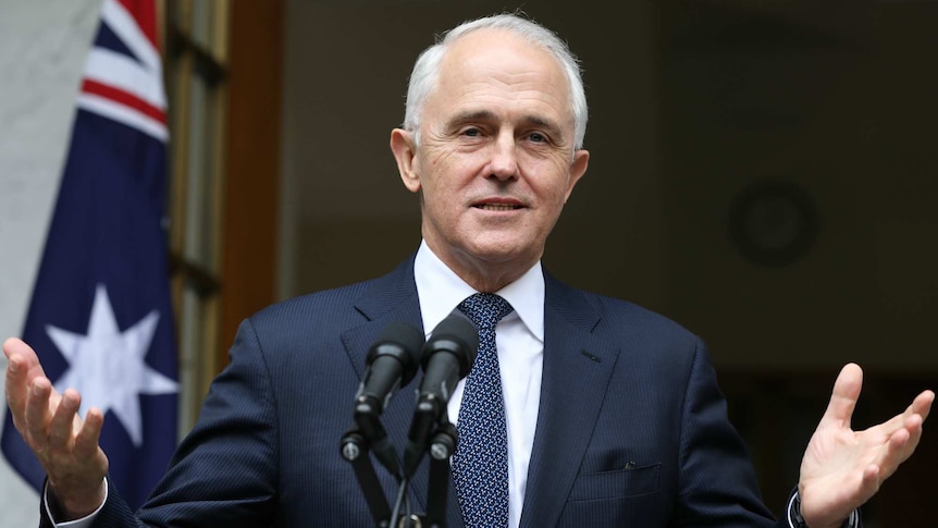 Malcolm Turnbull gives a speech with Australian flags in the background