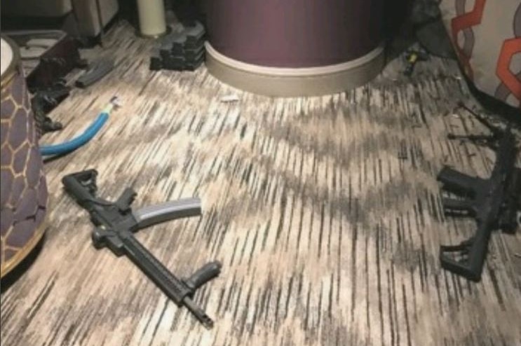 Two firearms are on brown carpet, with a hammer next to a pole in the background.