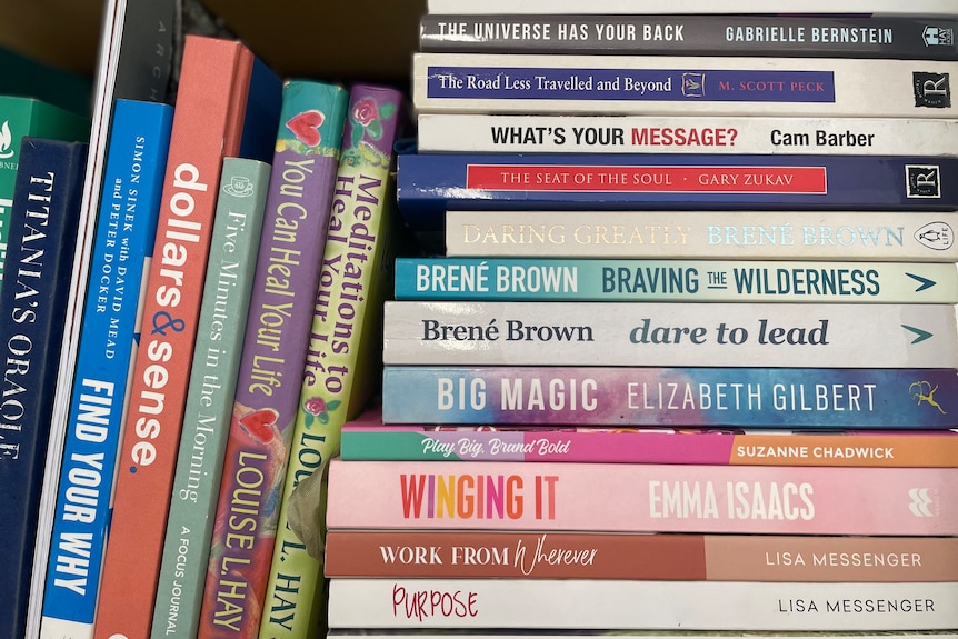 Self-help books piled on a bookself.