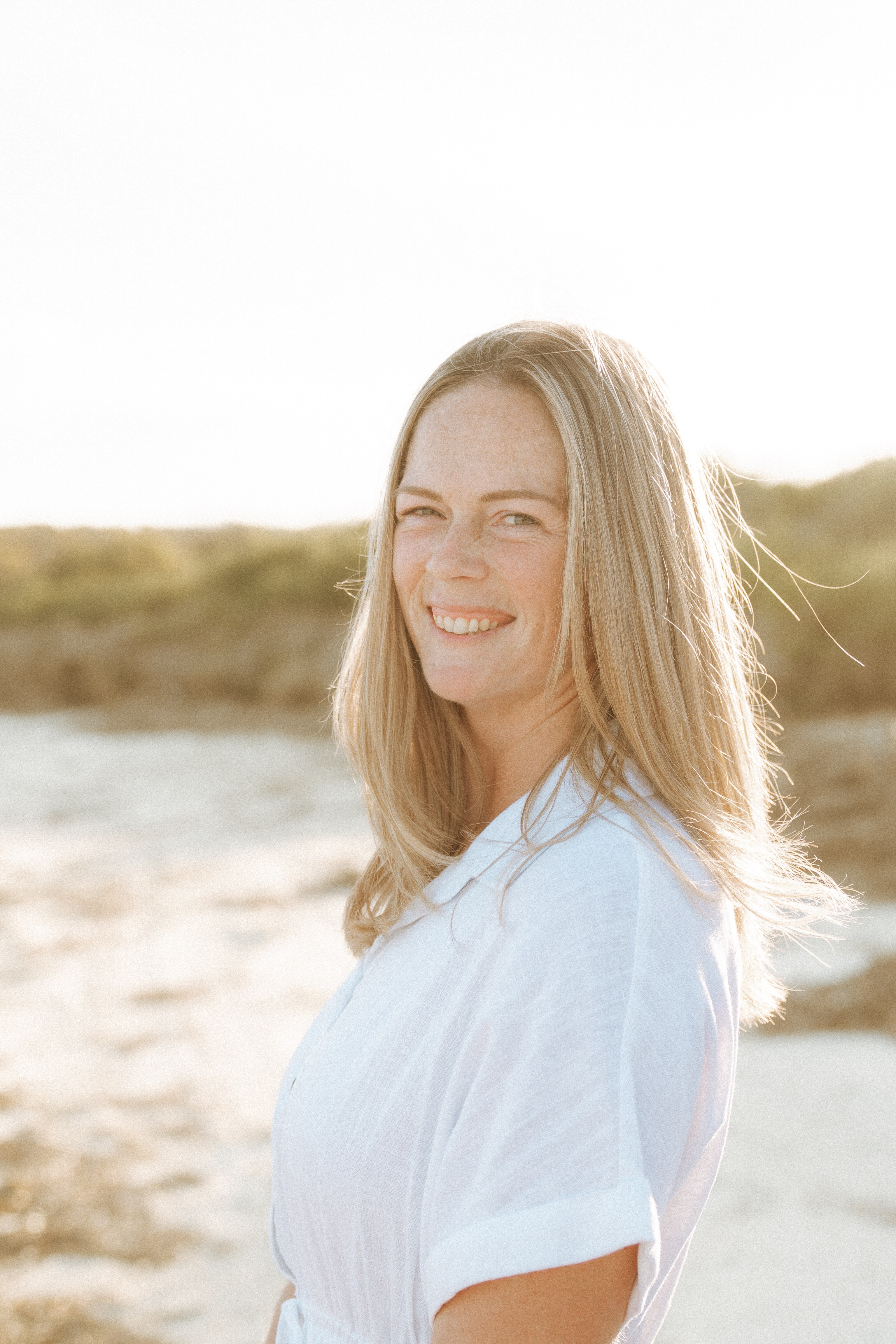 A woman standing on a beach smiling for the camera