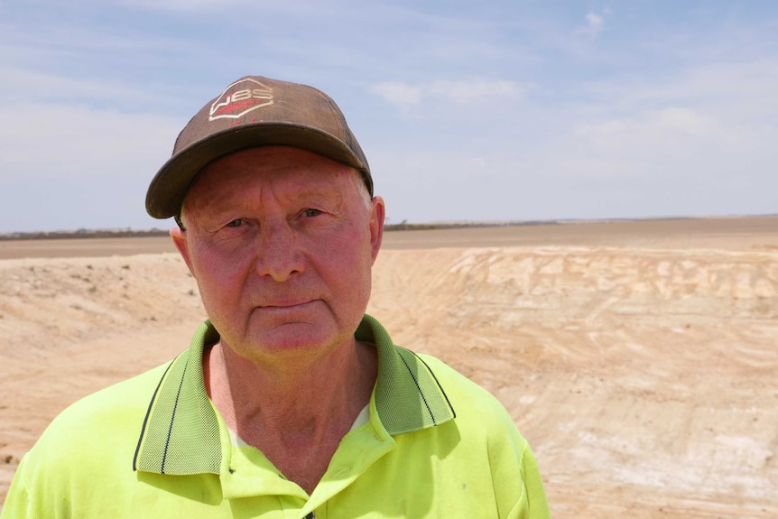 Lake Grace farmer Noel Bairstow stands at the edge of an empty dam.