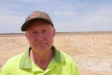 Lake Grace farmer Noel Bairstow stands at the edge of an empty dam.