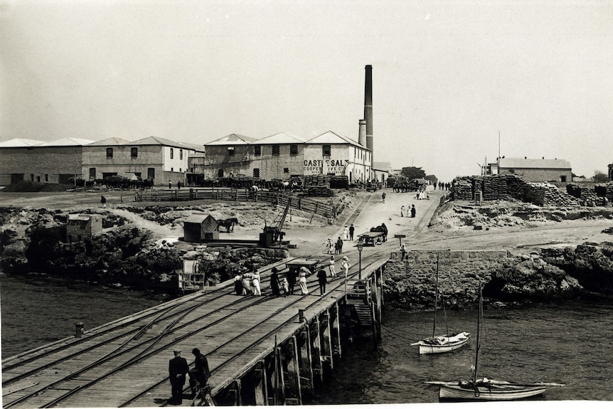 Black and white period photo of jetty scene with buildings in background