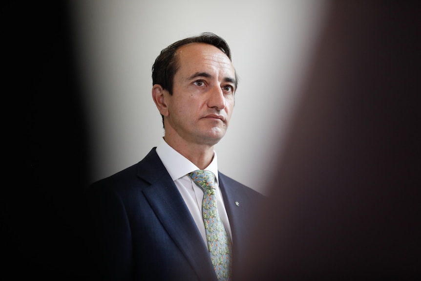 Man in suit with dark hair looking into mid distance