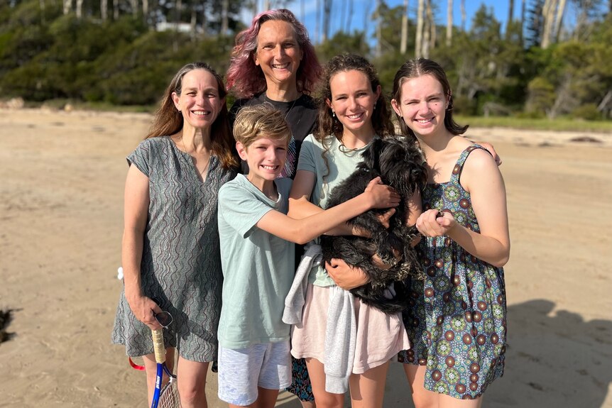 a family smiling with a dog on the beach