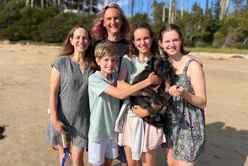 a family smiling with a dog on the beach