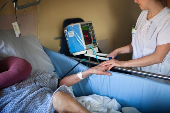 A nurse checking on a patient in a hospital bed.